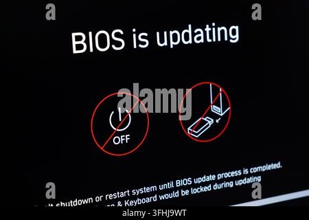 Poznan, Poland - February 15, 2026: The monitor shows a BIOS installation message with clear icons indicating that users must not turn off the machine Stock Photo