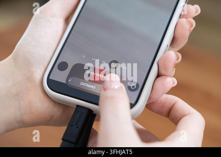 User managing mobile storage by selecting files on a phone linked to a portable ssd, demonstrating seamless digital content backup, fast file organiza Stock Photo
