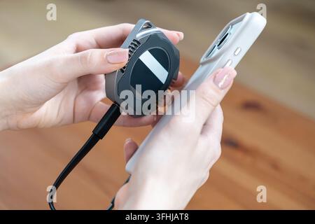 Close up of a hand holding a high performance portable SSD and a smartphone, symbolizing efficient media management and reliable mobile backup storage Stock Photo