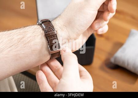 An individual secures a luxury timepiece with a dark crocodile pattern band, highlighting an appreciation for craftsmanship and elegance within a soph Stock Photo