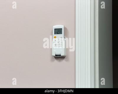 An electronic climate controller sits inside a sleek wall holder, displaying a digital setting to provide seamless regulation of interior heat or cool Stock Photo