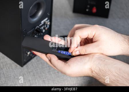 Hands install a new power cell into a wireless controller, demonstrating the quick process of preparing electronic household devices for reliable perf Stock Photo