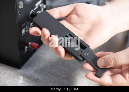 Close up of hands inserting a new power cell into a modern audio device controller, highlighting the essential setup process for maintaining functiona Stock Photo