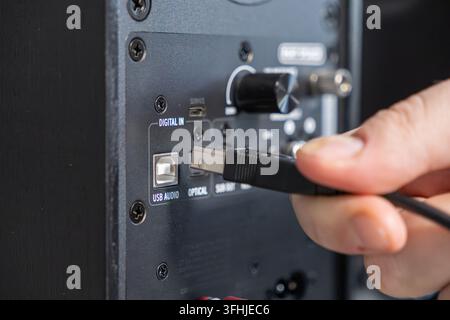 An individual inserts a connector into the rear panel of an electronic loudspeaker, illustrating professional hardware maintenance and the integration Stock Photo