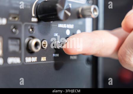 An index finger adjusting a metal audio selector toggle on a professional speaker interface, showcasing precision control during the installation of h Stock Photo