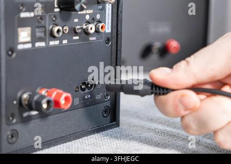 Close up of an electrical cord being connected to a studio monitor speaker, illustrating the simple installation of a professional home entertainment Stock Photo