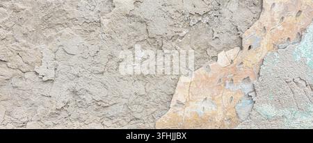 Rough concrete wall showing cracked surface and exposed paint layers Stock Photo