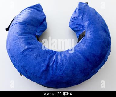 A blue plush Ushaped neck pillow rests on a white background Stock Photo