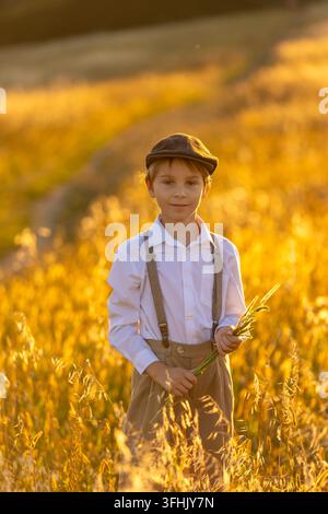 Sweet preteen child, boy, playing in a field on sunset with kite and old vingate car, walking with grandmother in the countryside, autumtime golden su Stock Photo