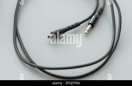 A black cable with micro USB and audio jack connectors rests on grey Stock Photo