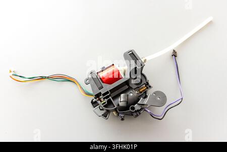 A small electronic pump with colorful wires is displayed on grey Stock Photo