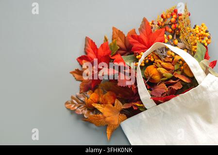 Top view of white bag with different autumn leaves with copy space for text over grey background. Autumn concept background Stock Photo