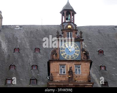 Ornate Renaissance clock tower on Marburg City Hall featuring a dual-ring face with Roman and Arabic numerals, stone sculptures, and bell cupola. Stock Photo