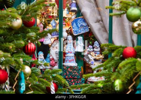 Handmade Christmas ornaments and toys on display, including Santa Claus and snowman figurines, framed by festive greenery and holiday decorations Stock Photo