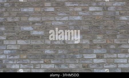 A background of textured gray-beige facing stone. A macro shot of the smooth texture of faux brickwork with uneven coloring. Perfect for construction Stock Photo