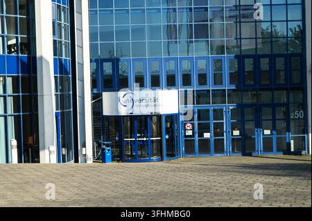Iserlohn, Germany - August 13, 2026: Revolving glass entrance door and modern blue facade of the Universitaet Witten Herdecke building. Stock Photo