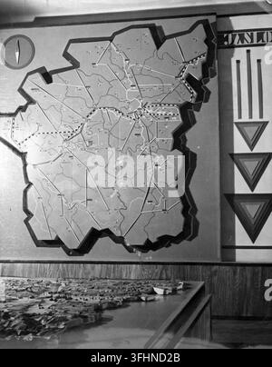A raised-relief map of the Jasło district, mounted on a wall, accompanied by a smaller three-dimensional terrain model and a vertical panel displaying geometric symbols and reversed text, including "JAXLO", in an indoor briefing or command room, 1943. Stock Photo