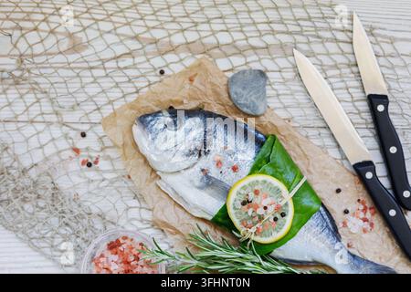 Whole Raw Gilthead Sea Bream Ready for Cooking with Lemon and Knives Stock Photo