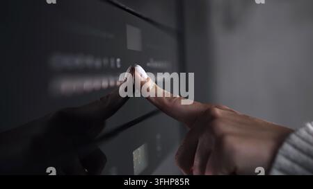 Female finger presses button on modern gas stove or oven. Woman cooking dinner in modern kitchen with equipment. Close-up view. Stock Photo