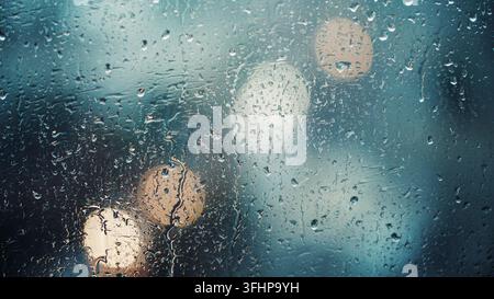 Close up view of water drops falling on glass. Rain running down on window. Rainy season, autumn. Raindrops trickle down, grey s Stock Photo