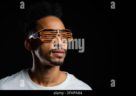 Portrait of african man in glowing neon glasses on black studio background. Positive smiling guy. Copy space. High quality photo Stock Photo