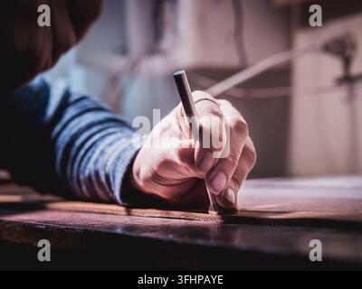 Close up of leather craftsman working with natural leather using hammer. Handbag master at work in local workshop. Handmade concept. Male shoemaker cr Stock Photo