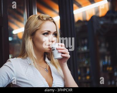 Portrait of young woman drinking coffee while enjoying her leisure time alone, business woman lunch in cafe during work break Stock Photo