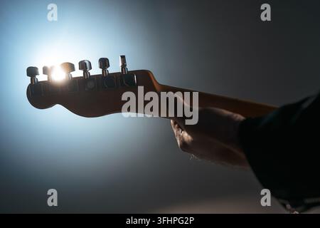 Guitar neck. Close-up view of rock musician man playing electric guitar. Smoky spotlight during concert on stage. Stock Photo