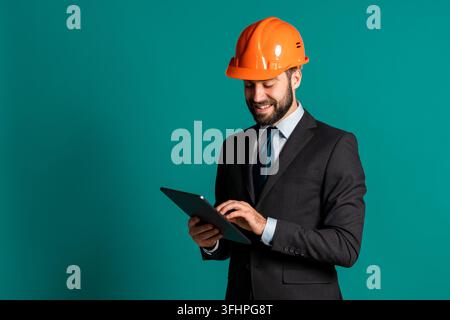 Young engineer businessman in suit jacket makes notes on paper building project, report. Businessman isolated on blue background as on construction. H Stock Photo
