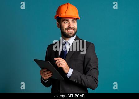 Young engineer businessman in suit jacket makes notes on paper building project, report. Businessman isolated on blue background as on construction. H Stock Photo