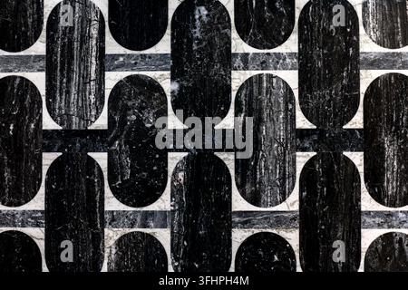 Black and White Geometric Marble Tile Pattern. Close-up of black, gray and white marble tiles arranged in a bold geometric pattern with rounded Stock Photo