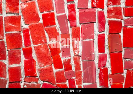 A close-up macro of a vibrant red glass mosaic. The frame is filled with irregularly shaped pieces of glass in a variety of red hues, including bright Stock Photo