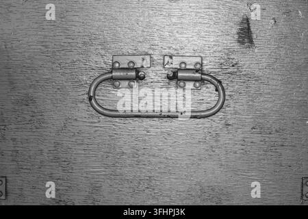 Black and white metal handle on wooden surface with screws Stock Photo