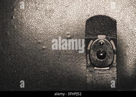 Vintage metal snap button clasp on dark grainy leather suitcase Stock Photo