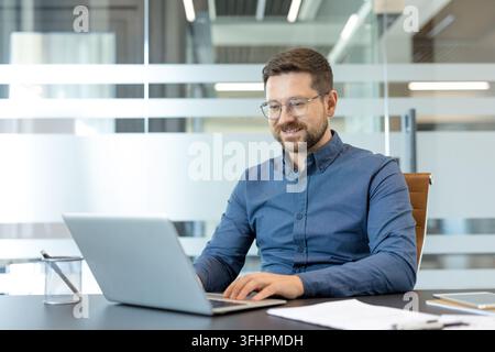 Remote work and digital transformation, professional man working on laptop in modern office with corporate productivity and business communication. Focused businessman using technology for daily. Stock Photo