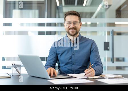 Professional businessman working on laptop in modern office, corporate employee using computer for business strategy and financial planning. Stock Photo