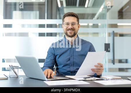 Professional businessman working in office, corporate employee using laptop and reviewing documents for business strategy and financial planning. Stock Photo