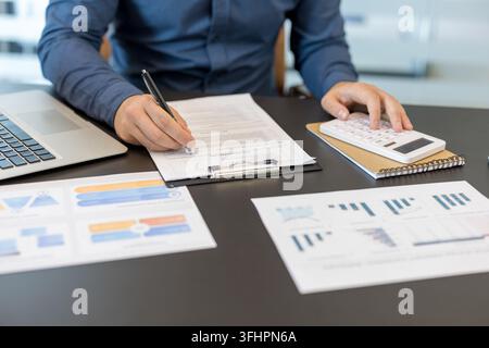 Financial planning and business analysis, professional accountant working with calculator and financial reports on office desk. Detailed review of corporate performance and revenue statistics. Stock Photo