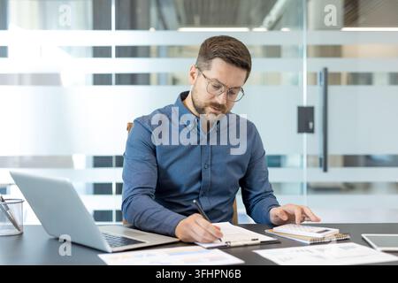 Financial planning and business analysis, professional man working with laptop and calculator in modern office for corporate accounting and budget management. Stock Photo