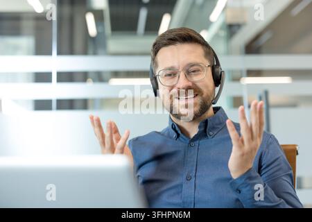 Customer support representative talking on video call, remote work and online communication with professional man using headset in office. Stock Photo