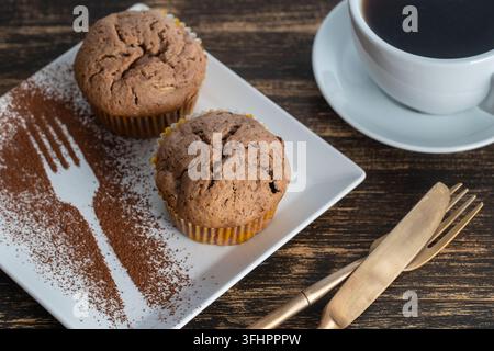 Sweet cherry muffin and white cup with tea on a wooden background, close up Stock Photo
