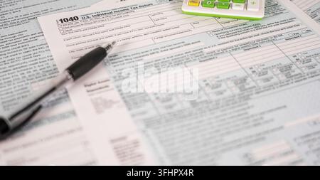 A close-up view of the U.S. Individual Income Tax Return Form 1040, with a pen resting on it and a calculator in the background, symbolizing financial Stock Photo