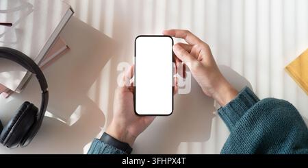 Top view mockup image of a woman holding mobile phone with blank white screen while sitting Stock Photo