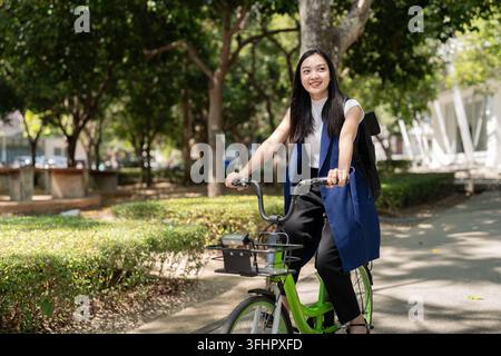 Asian businesswoman in bicycle go to work at office. Bike commuting, happy businesswoman using eco transport, Concept of eco lif Stock Photo