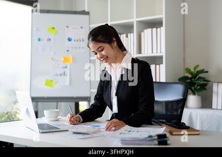 Businesswoman accountant using calculator and laptop for financial data saving in office room, Business financial, tax, accounti Stock Photo