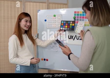 Ux developer and ui designer presenting mobile app interface design on whiteboard in meeting at office. Creative digital develop Stock Photo