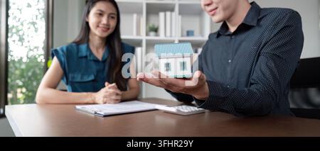 Real Estate Agent Presenting House Model to Client in Office Setting for Property Sale or Purchase Stock Photo