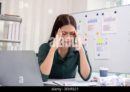 Stressed Businesswoman at Office Desk with Laptop and Documents, Experiencing Work Pressure and Fatigue Stock Photo