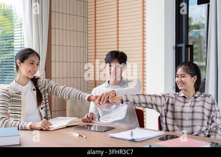 Three students working together, sharing ideas, and studying in a bright, modern classroom environment. Stock Photo