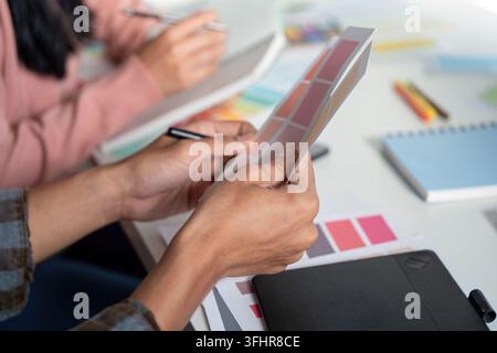 A vibrant design team collaborates on graphics in a modern office fostering creativity and innovation in their projects. Stock Photo